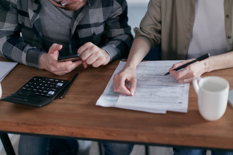 Dwoje ludzi przy stole z dokumentami i kalkulatorem